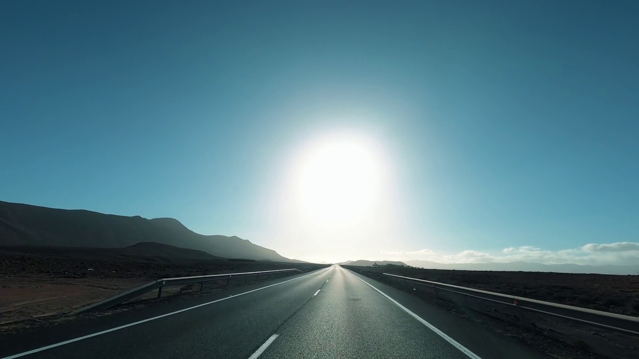 在路上旅行的概念。空长直路和交通概念。背景是落日。阳光照在柏油路上。蓝天碧山风景区。旅行者的生活方式和自由视频素材