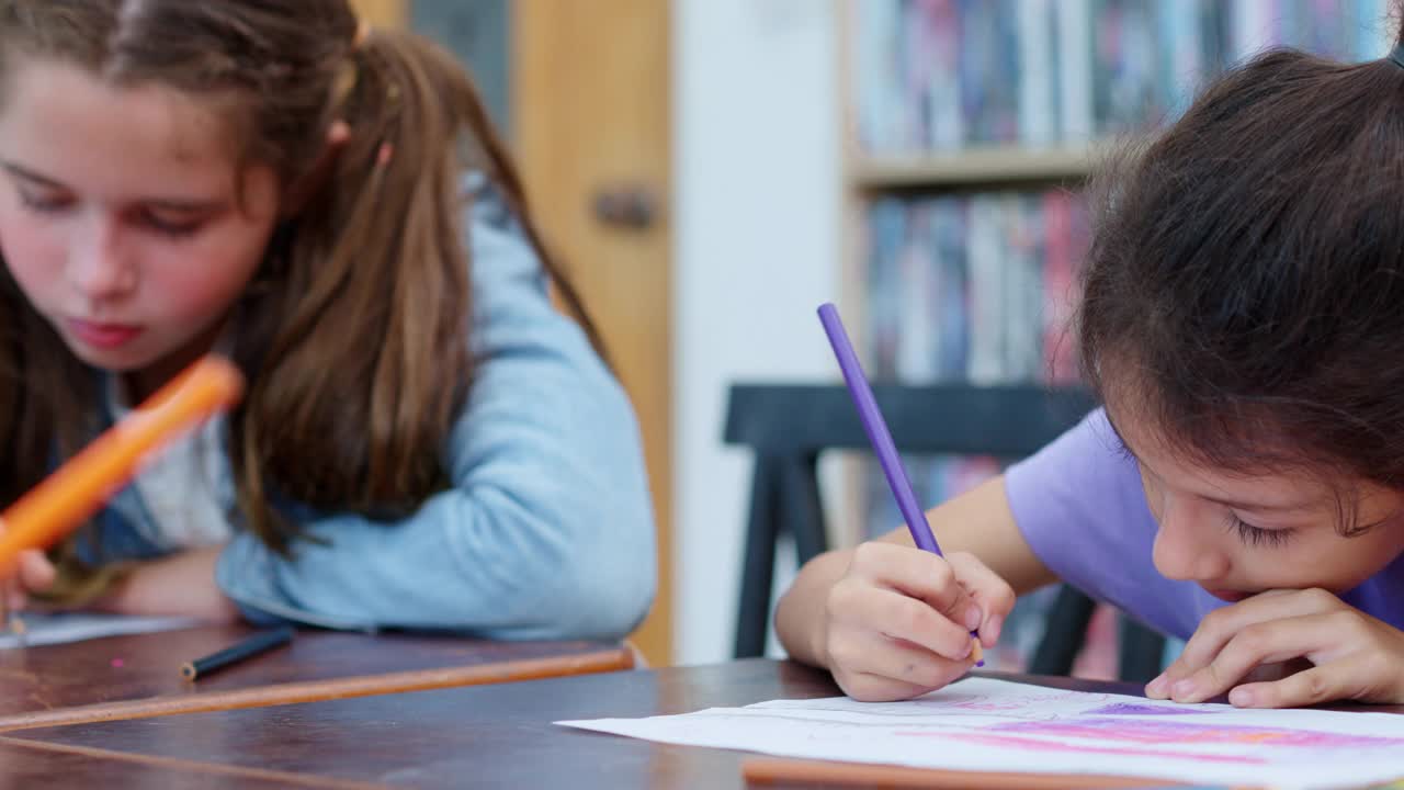 2名白人小学女生正在美术课上学习，正在纸上画画。视频素材