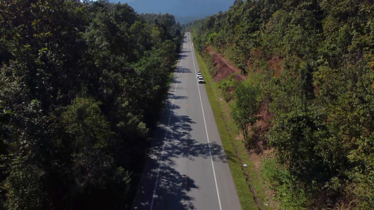 在一个明亮的日子里，在秋天的森林中有笔直的道路的Doi Luang Chiang Dao山的空中景观。视频素材