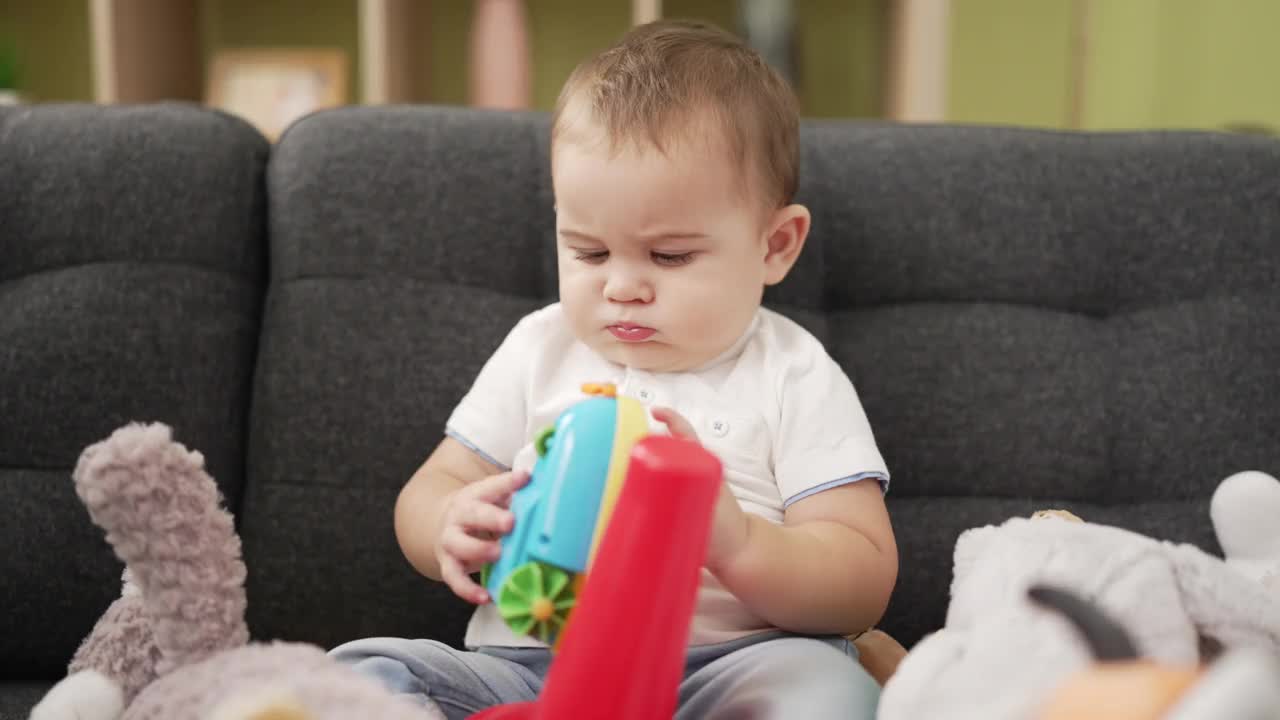 可爱的幼儿坐在家里的沙发上玩玩具视频素材