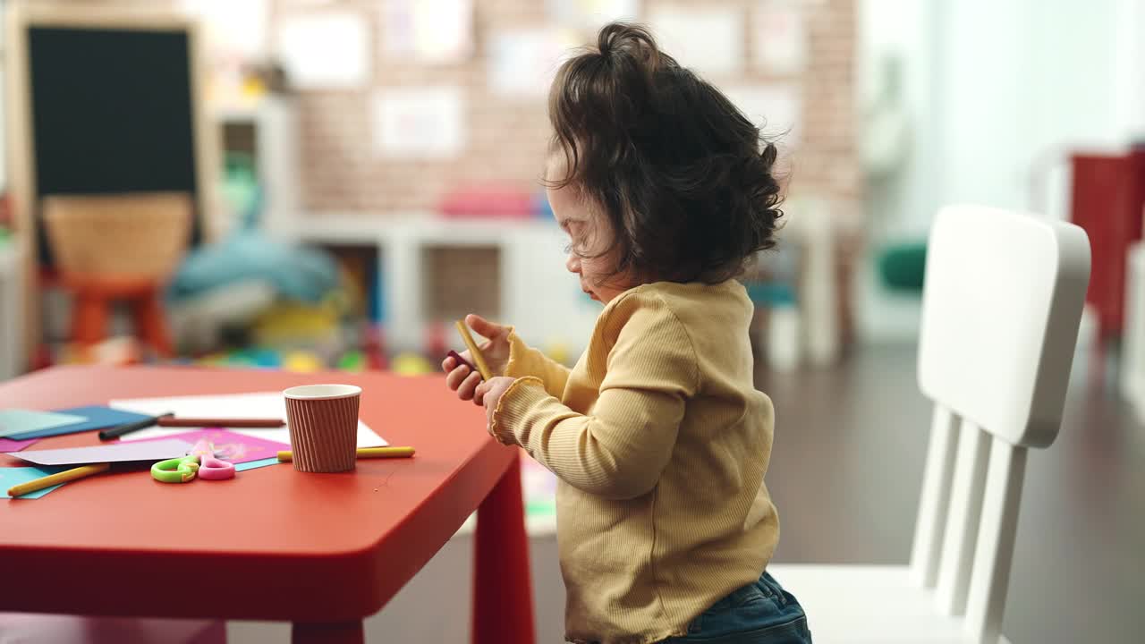 可爱的西班牙女孩学生坐在桌子上把铅笔颜色的杯子在幼儿园视频素材