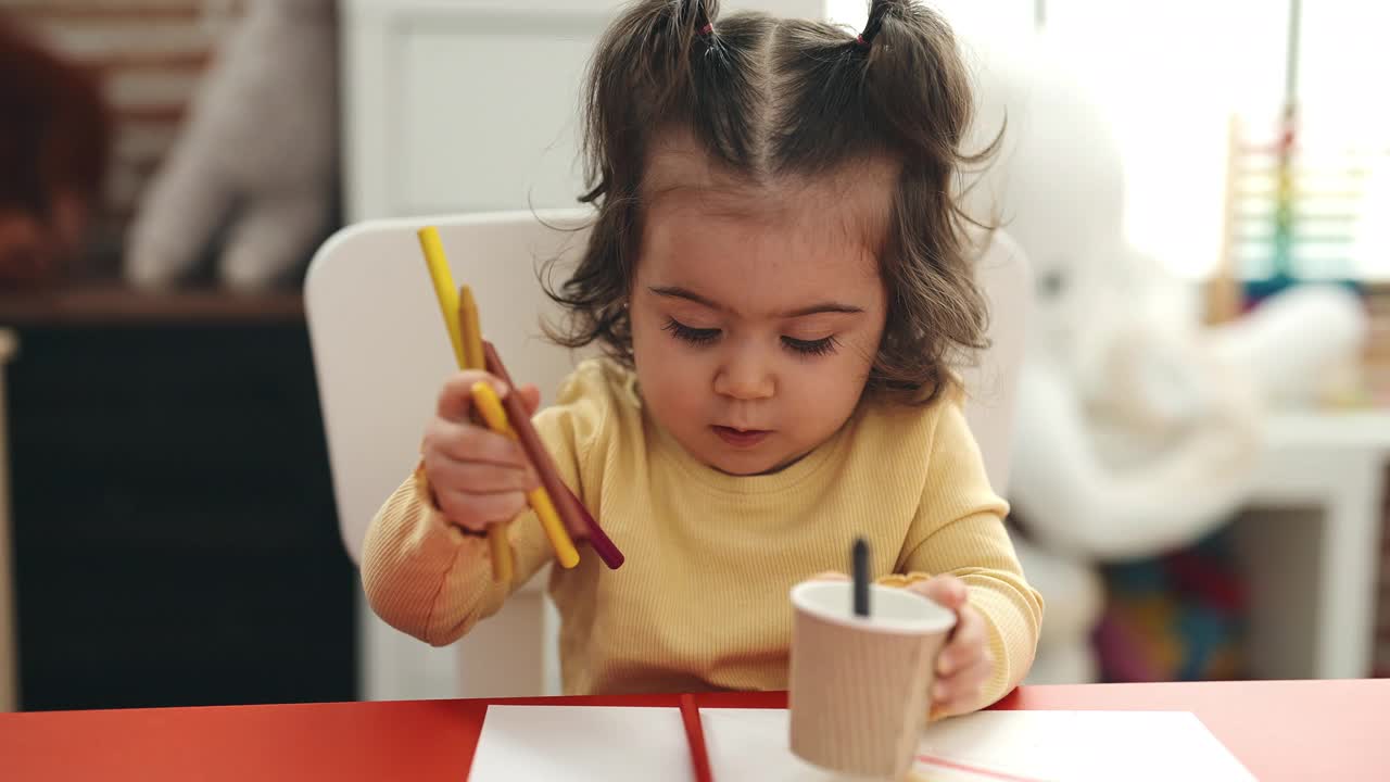 可爱的西班牙女孩学生坐在桌子上把铅笔颜色的杯子在幼儿园视频素材