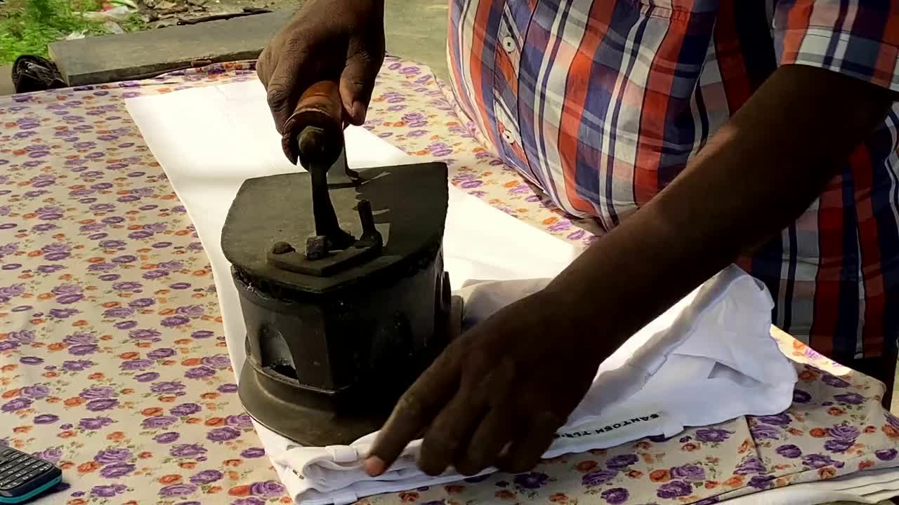 男人用手在熨衣板上熨烫白色的裤子领子，在洗衣房熨烫衣服视频素材