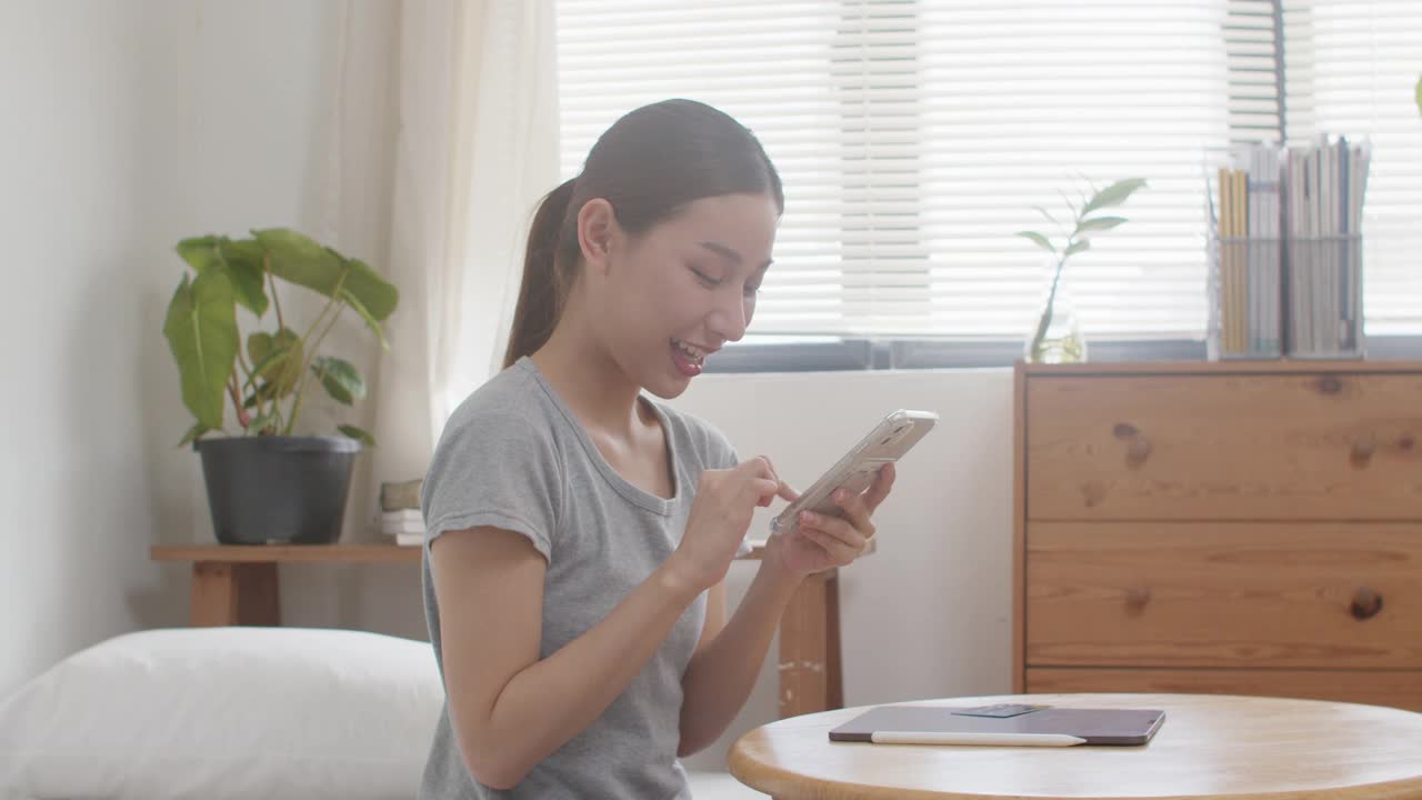 年轻的亚洲女子在家购物后使用智能手机进行在线支付。美女输入信用卡号码进行网上支付购物。视频素材