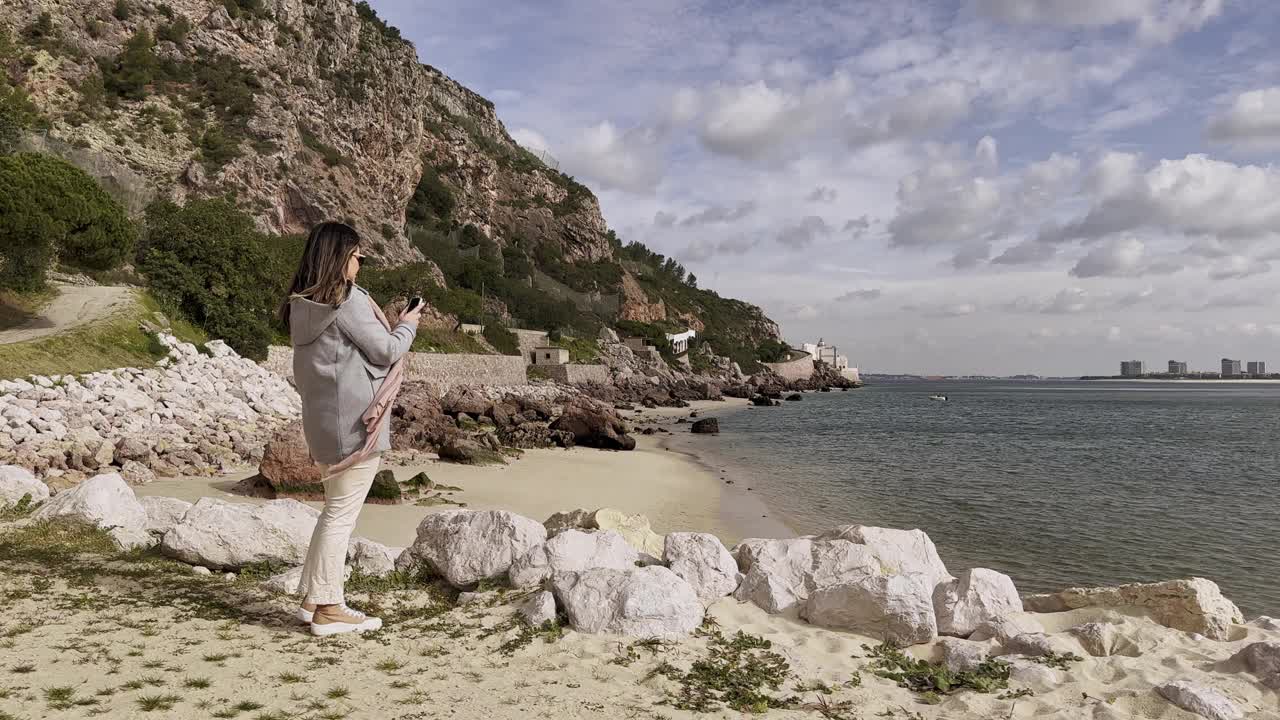 欧洲冬天，一名女子在海滩上使用智能手机视频素材