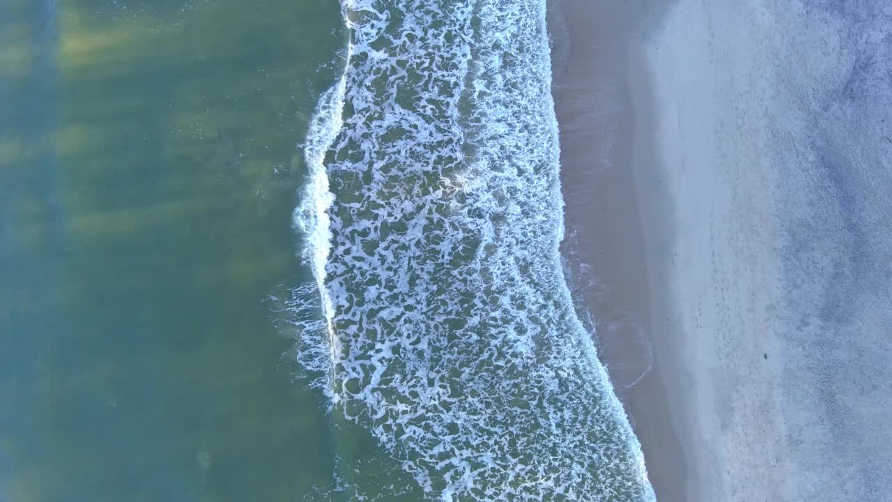 沙滩上的泡沫海浪。无人机在上方平移视频素材