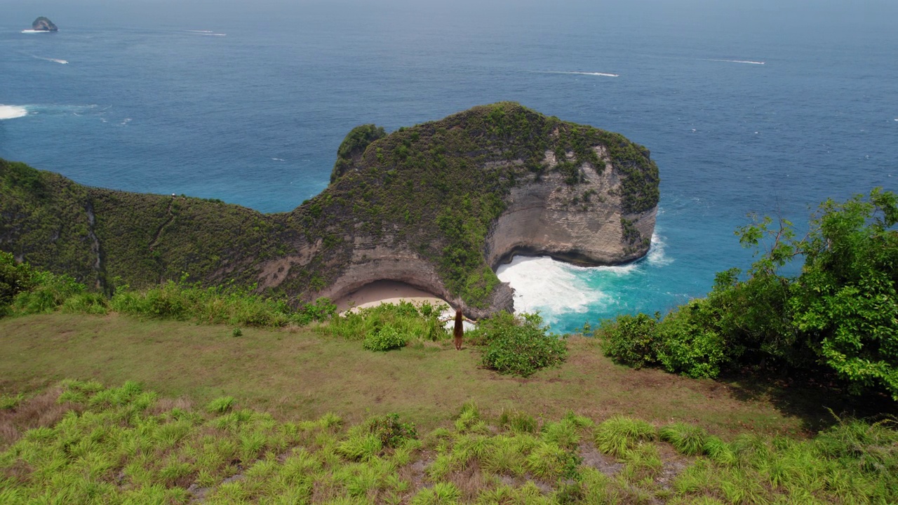 空中海景柯灵京海滩努萨佩尼达岛和年轻女子站在山顶陡峭的悬崖。视频素材