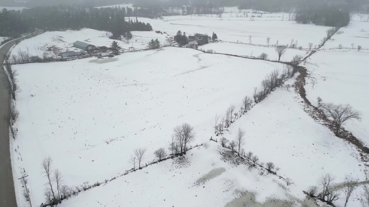 无人机在山上拍摄美丽的冬季景色，远处的松树被雪覆盖，农场。黑暗的天空下着大雪。电影的拍摄。冬季旅游。视频素材