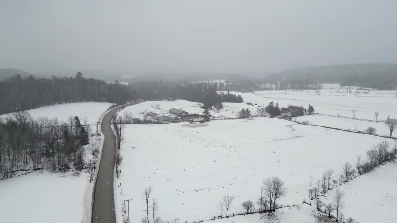 无人机在山上拍摄美丽的冬季景色，远处的松树被雪覆盖，农场。黑暗的天空下着大雪。电影的拍摄。冬季旅游。视频素材