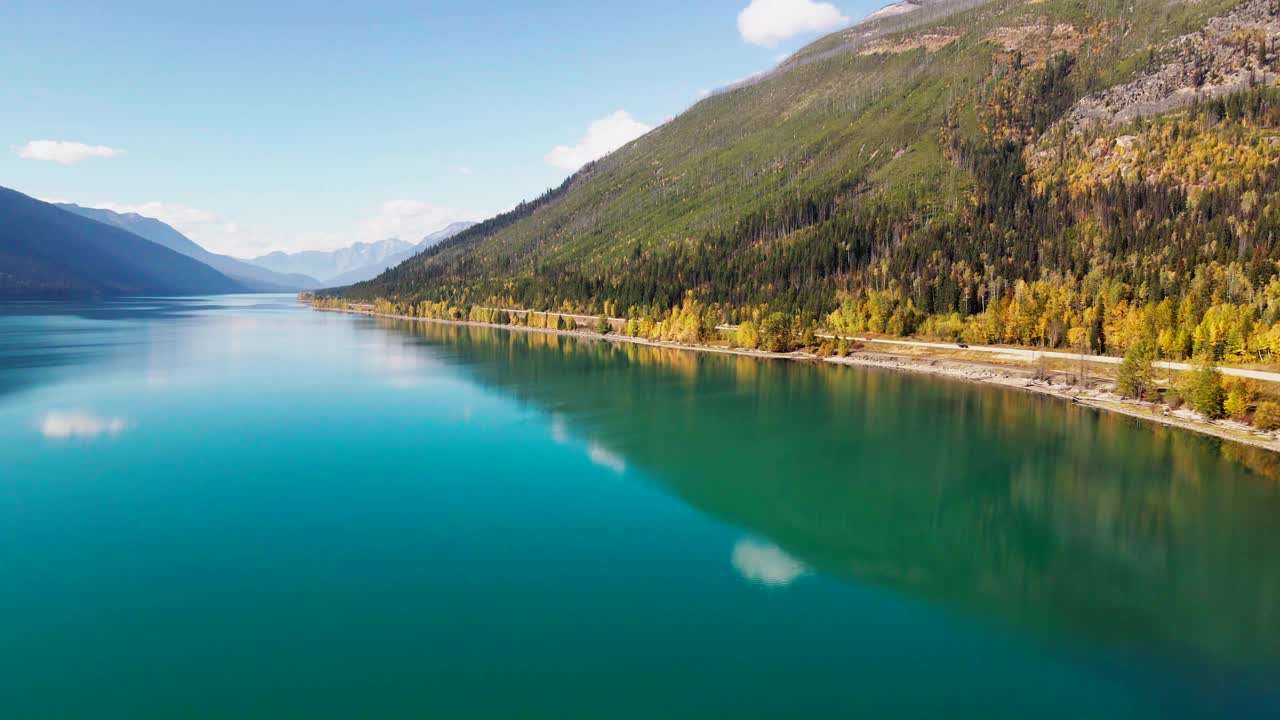 秋天罗布森山省立公园的驼鹿湖，背景是黄色的树木和山脉，汽车行驶在有蓝绿色水的高速公路上视频素材