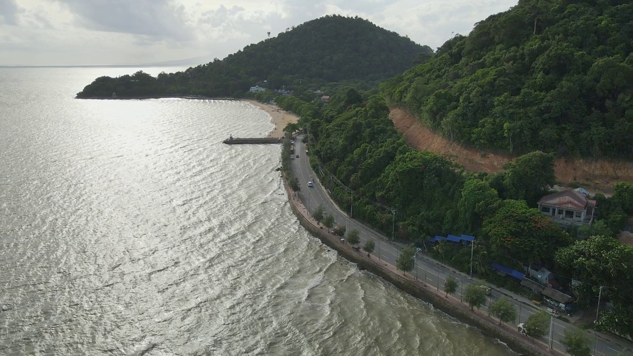 空中向后飞行的镜头，揭示阳光与阴影在表面海浪沿海岸公路视频素材