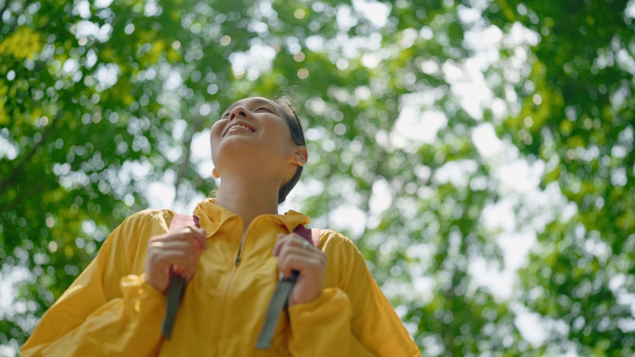 穿着黄色雨衣的背包女徒步旅行者视频素材