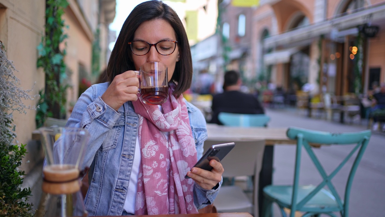 Young woman using smart phone in a sidewalk café视频素材