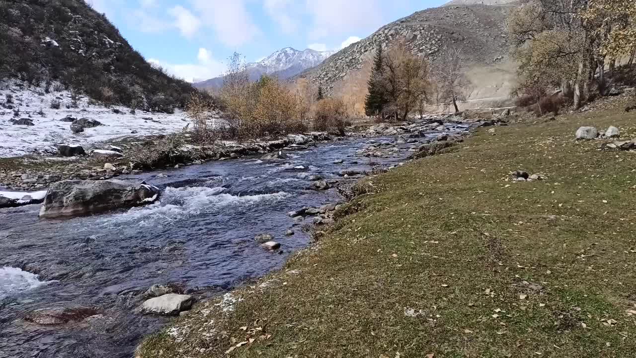 高山脚下的一个小海岸，海岸上覆盖着初雪。视频素材