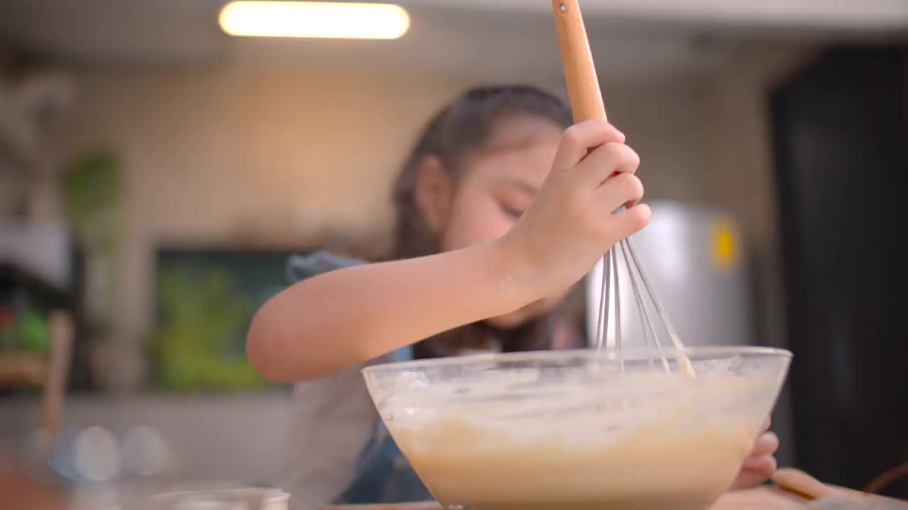 女孩帮妈妈搅拌面粉烘焙。视频素材