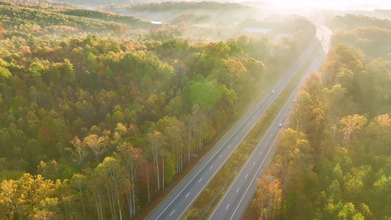 鸟瞰繁忙的美国高速公路与快速移动的交通包围的秋天森林树木。州际运输概念视频素材