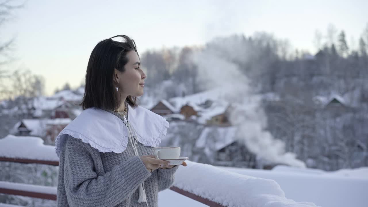 一个女孩在寒冷的院子里喝茶。冬天的早晨视频下载