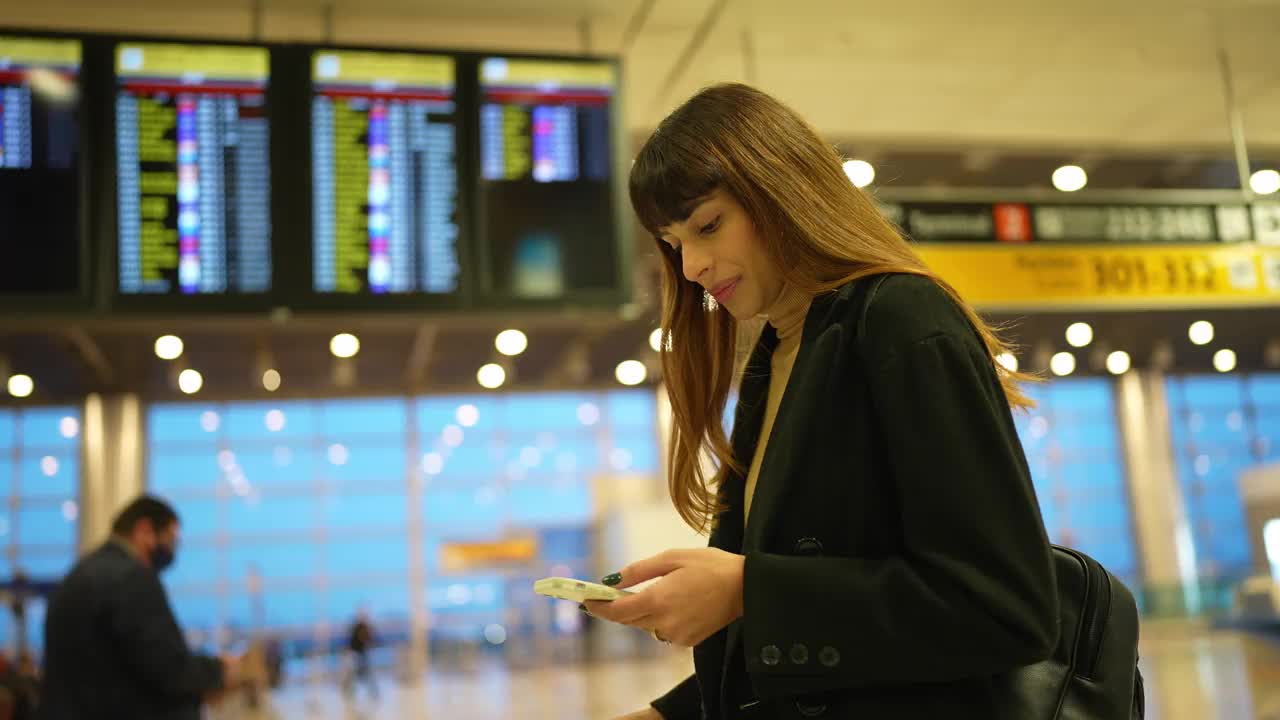 年轻女子在机场检查登机牌和使用智能手机视频素材