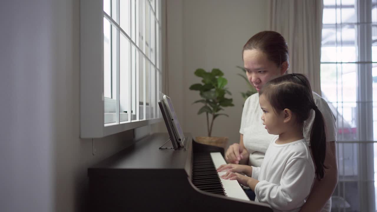 小女孩和妈妈一起练习钢琴视频素材