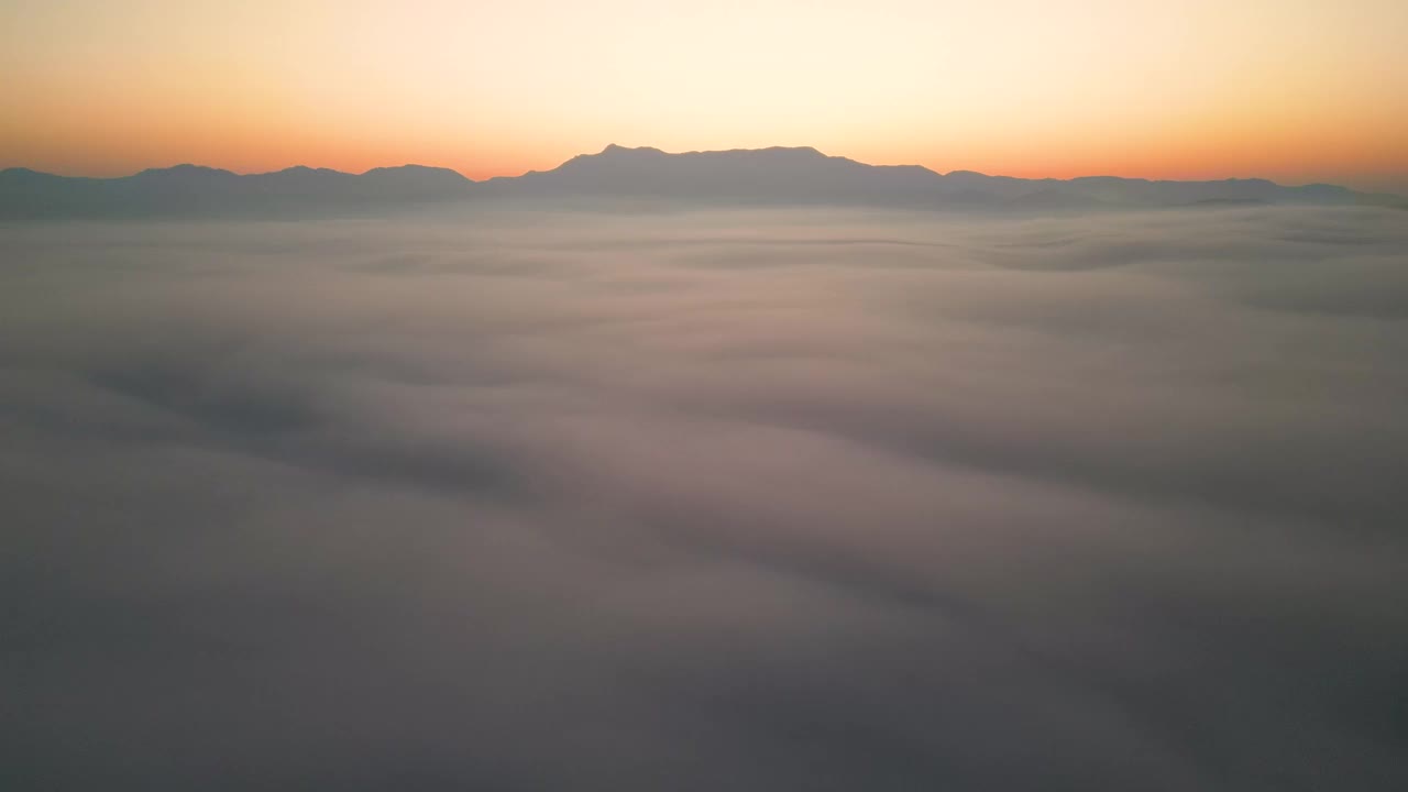 空中拍摄的云和移动的雾在山上与日出视频素材