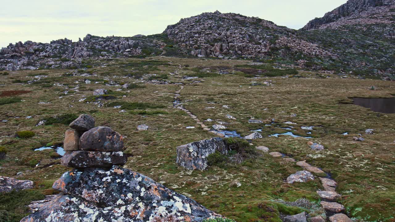 固定的镜头的年轻人徒步旅行在一个宏伟的景观场景与山脉的背景在塔斯马尼亚的荒野视频素材