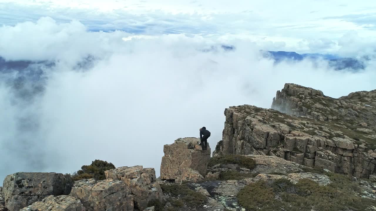 一名年轻男子在一个以迷雾山脉为背景的大风景中拍照视频素材