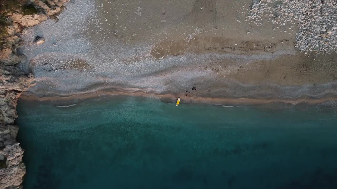 一个男人在一个美丽的海湾的荒野海滩上的SUP板视频下载