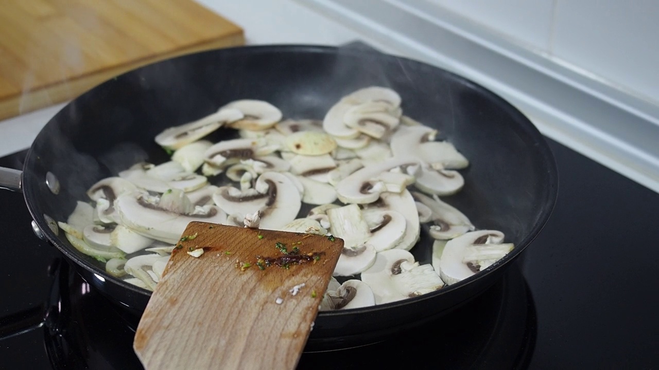 视频4k烹饪蘑菇在锅与木调色板在真正的厨房视频素材