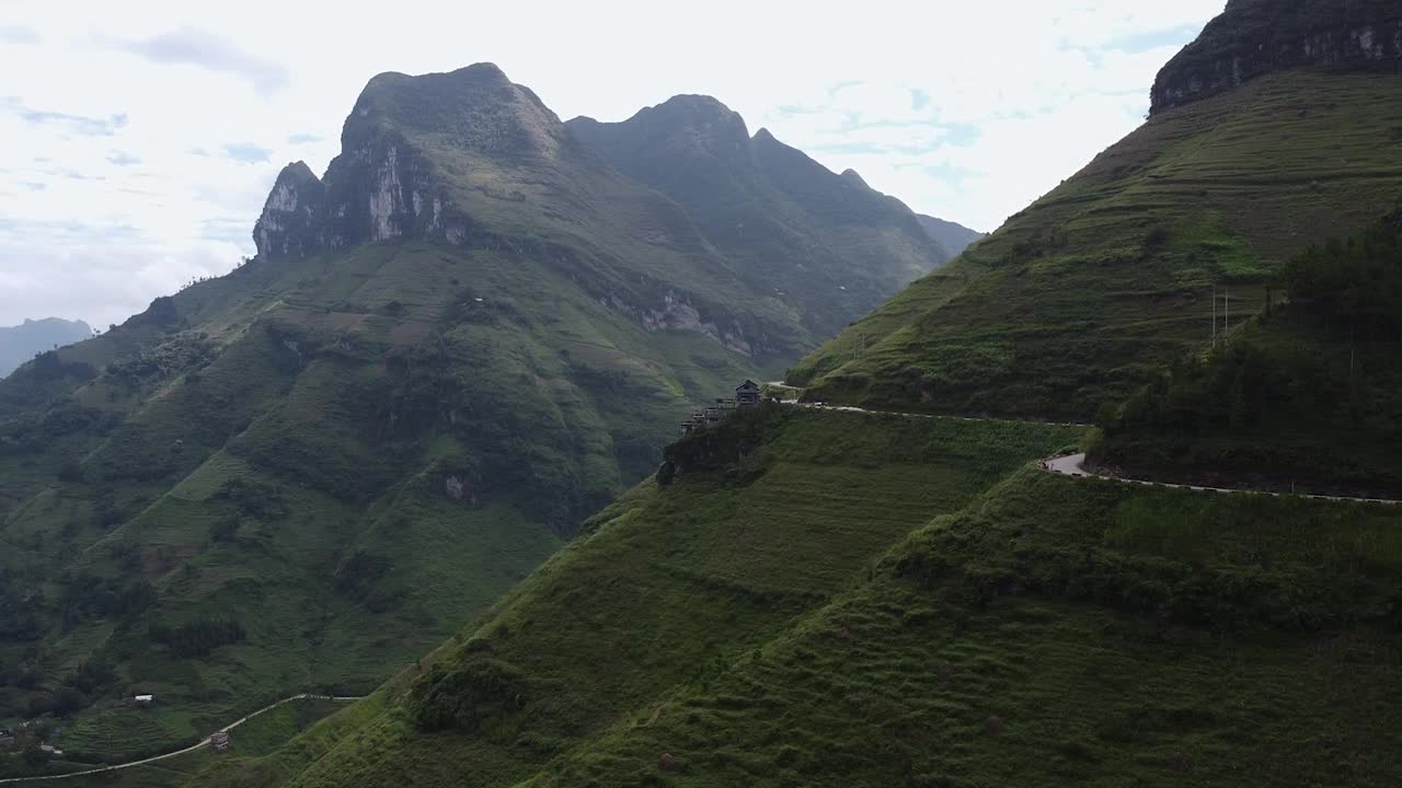 鸟瞰一条美丽的曲线公路，在高山之间，周围是绿色的森林和水稻种植园视频素材