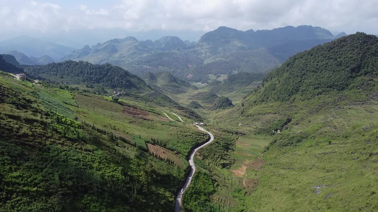 鸟瞰一条美丽的曲线公路，在高山之间，周围是绿色的森林和水稻种植园视频素材