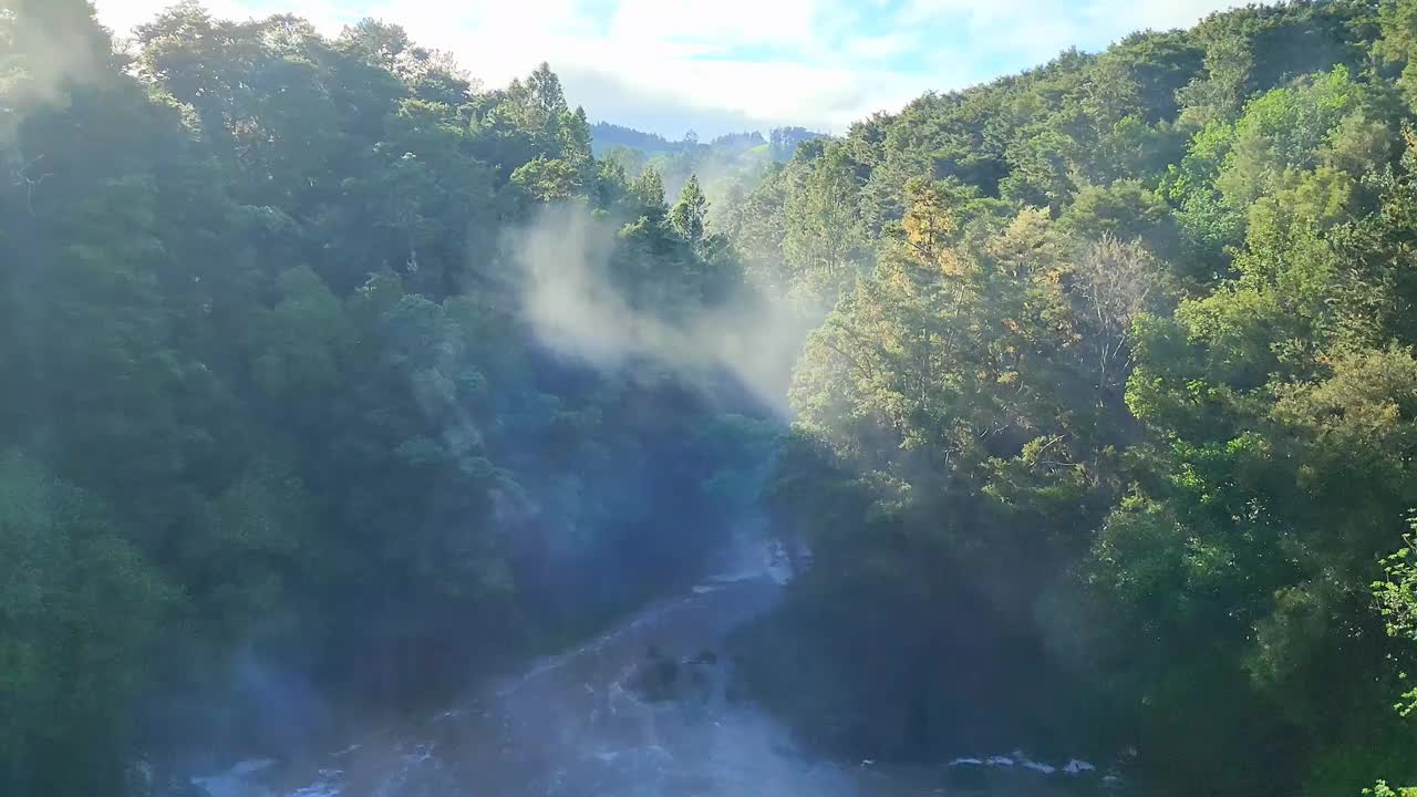 在阳光明媚的日子里，水滴和瀑布的泡沫被绿树包围着视频素材