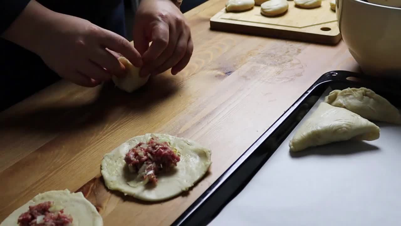 女性手把切碎的馅放在酥皮里，这是自制食物，传统上是做萨姆沙视频素材