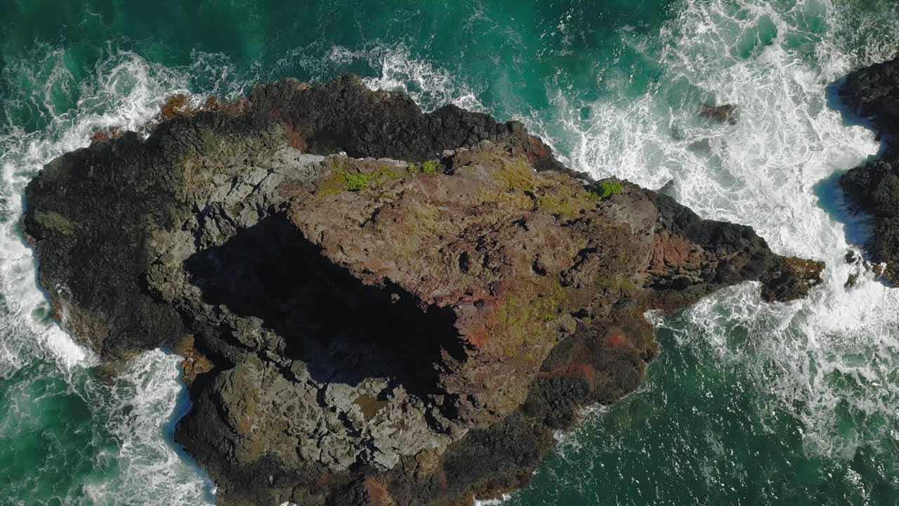 在夏威夷毛伊岛一个阳光明媚的日子里，海浪撞击一个小岛的无人机视图视频素材