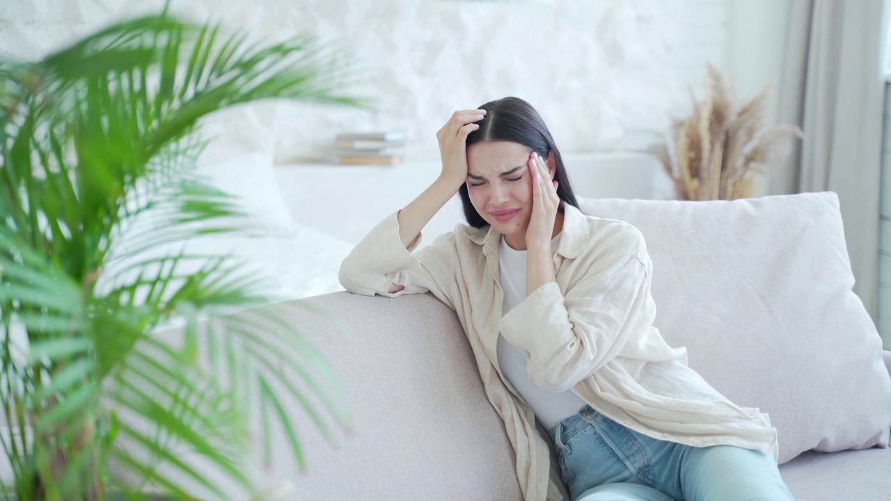 哭泣悲伤的女人感到不快乐的心理问题，分手或硬离婚坐在沙发上在明亮的客厅。视频素材