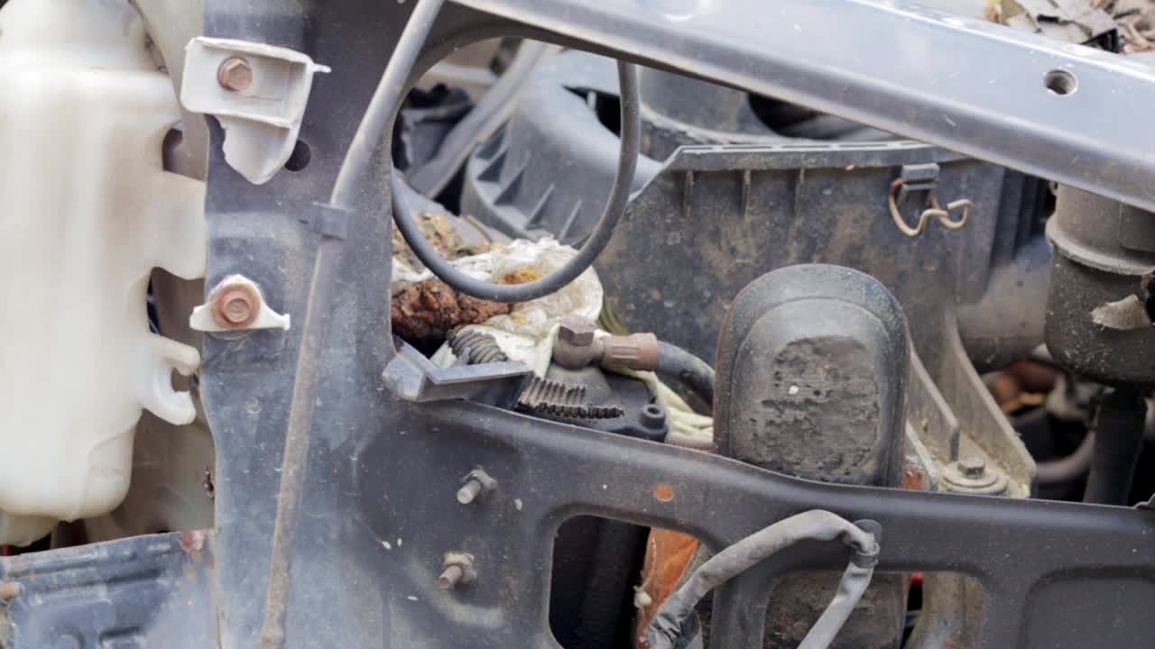 交通事故后损坏的汽车。汽车保险概念。破损的汽车。一个玩具在一辆被烧毁的汽车引擎盖下的零件和管道中。视频素材