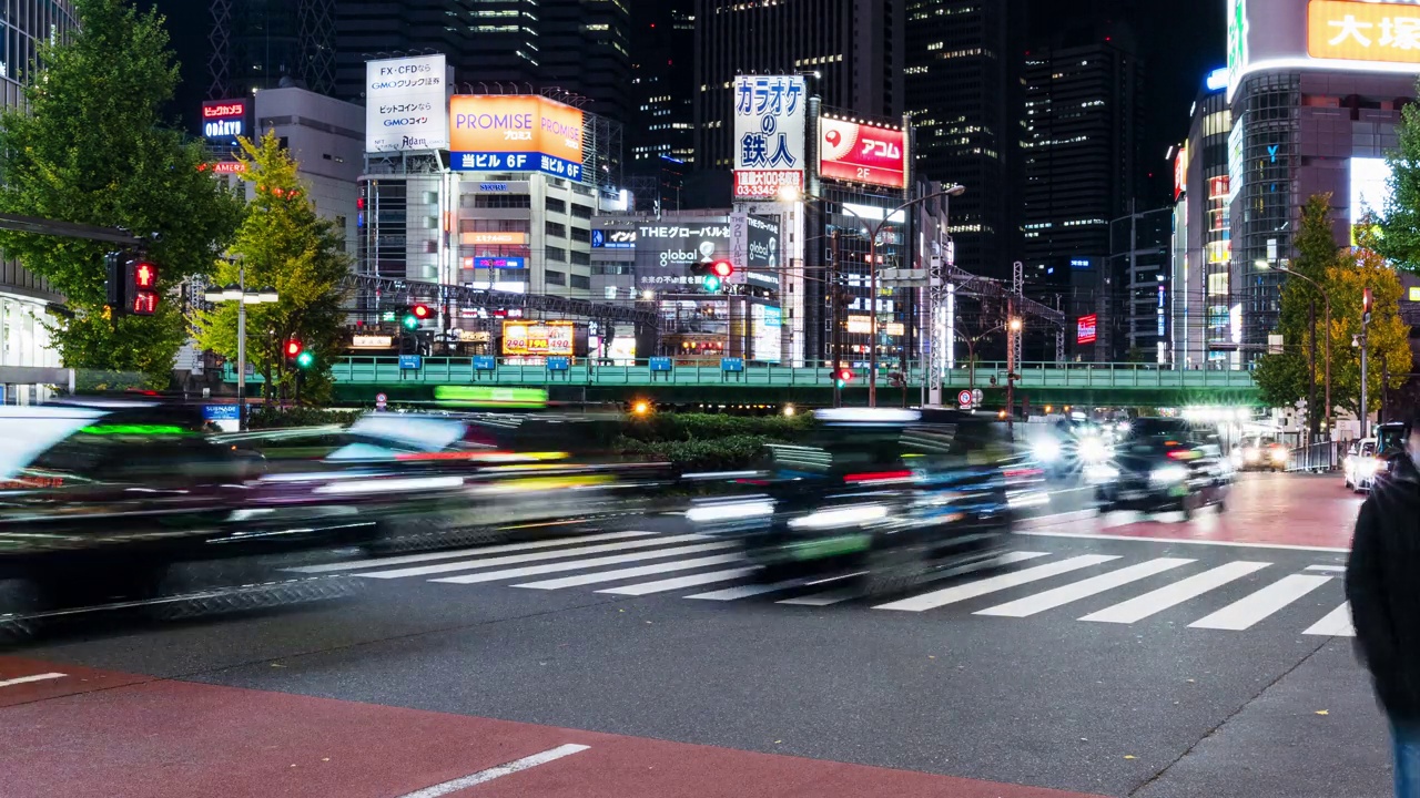 夜间汽车时间流逝，火车交通运输，日本人步行穿过斑马线在日本东京新宿歌舞伎町，办公大楼的城市景观。亚洲交通，亚洲城市生活理念视频素材