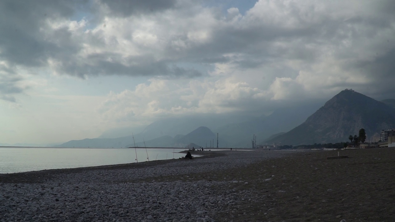 海边的渔民。海岸与山脉和多云的天空为背景。视频下载