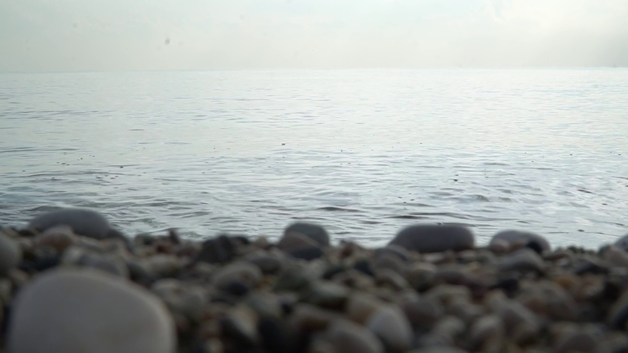 天际线，大海，天空和卵石海岸。平静的海水和模糊的卵石海滩视频下载