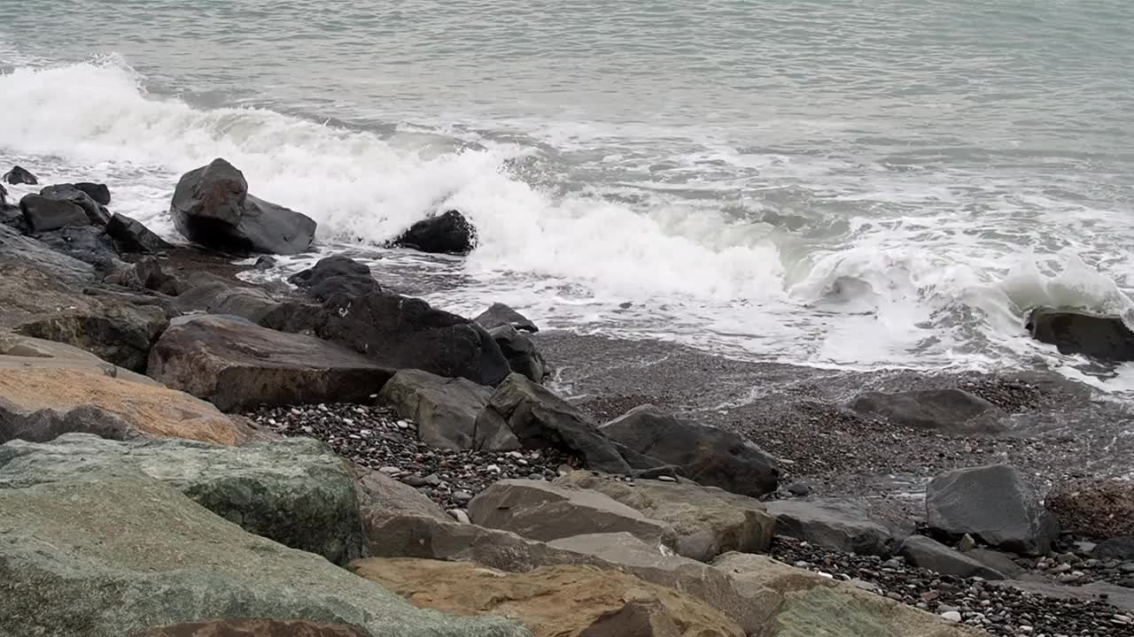 波浪撞击着岸边的巨石。阴暗的天气。在风暴到来之前，洛基海滩已经过季了。视频素材