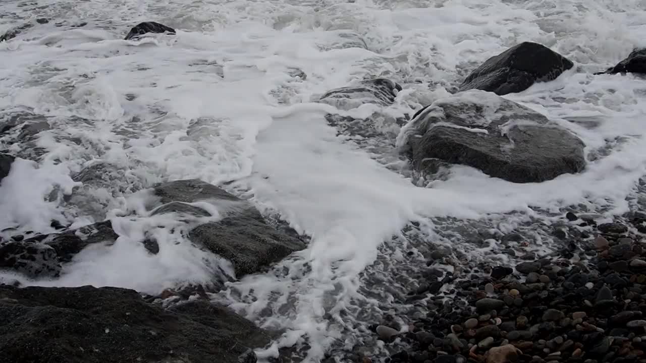 波浪撞击着岸边的巨石。阴暗的天气。在风暴到来之前，洛基海滩已经过季了。视频素材