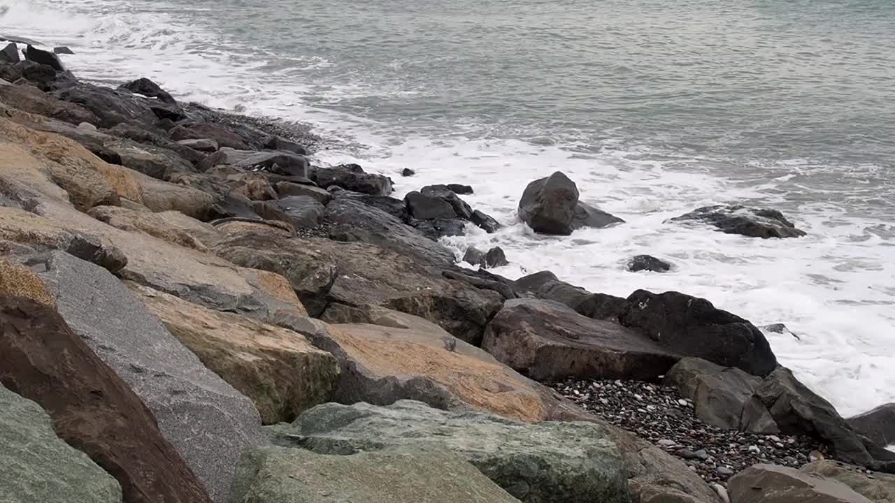 波浪撞击着岸边的巨石。阴暗的天气。在风暴到来之前，洛基海滩已经过季了。视频素材