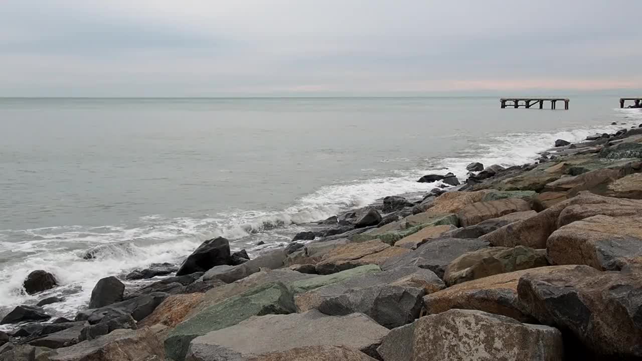 波浪撞击着岸边的巨石。阴暗的天气。在风暴到来之前，洛基海滩已经过季了。视频下载