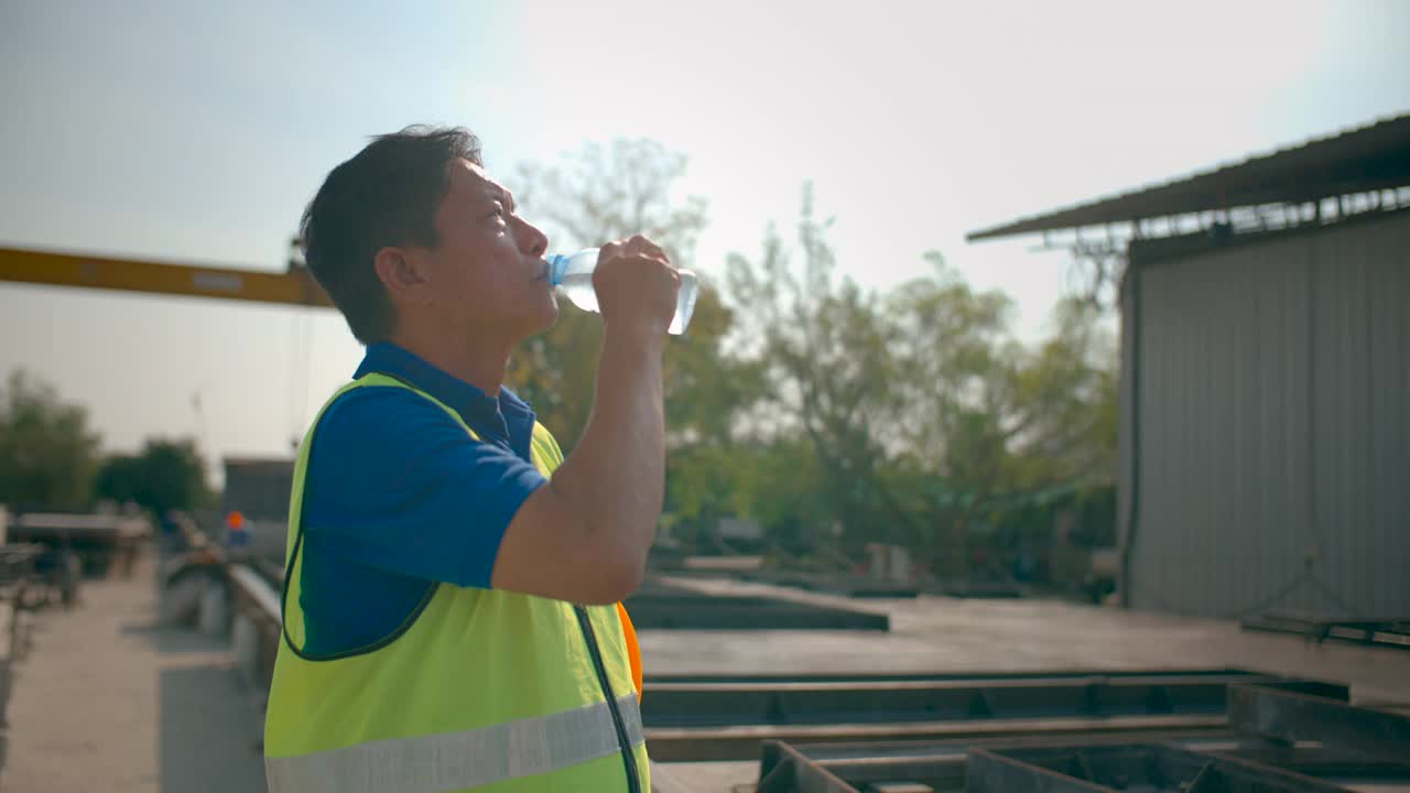 建筑工人站在室外喝水。视频素材