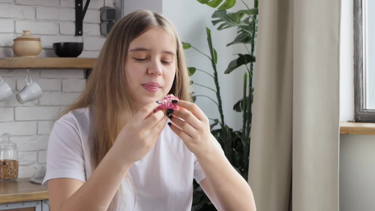 一个患有饮食失调症的女孩很快就吃了一个甜甜圈。女学生贪婪地吃着甜甜圈。甜食成瘾和暴饮暴食的概念视频素材