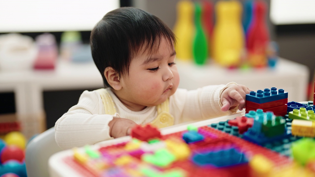 可爱的西班牙宝宝坐在幼儿园的桌子上玩积木视频素材