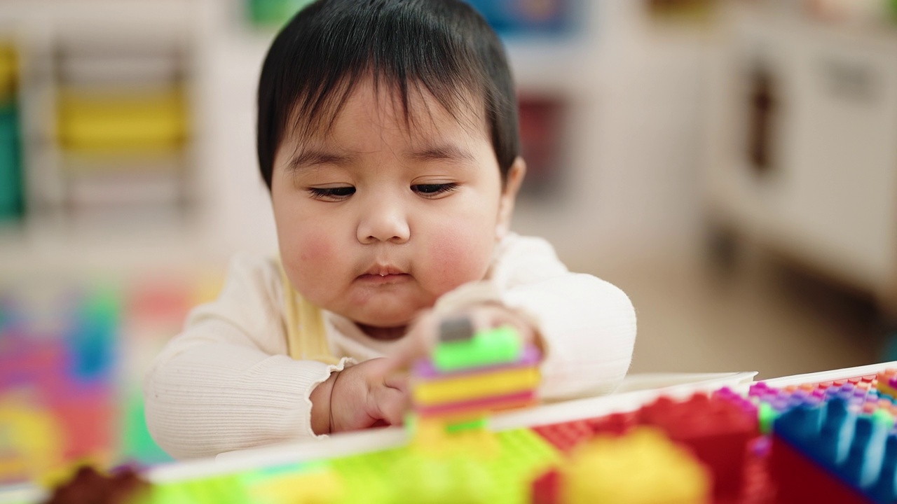 可爱的西班牙宝宝坐在幼儿园的桌子上玩积木视频素材