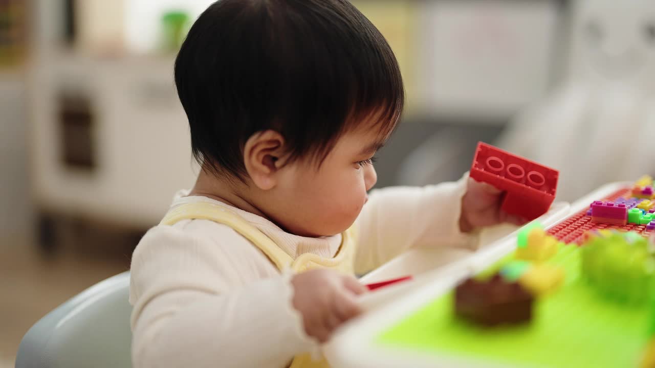 可爱的西班牙宝宝坐在幼儿园的桌子上玩积木视频素材