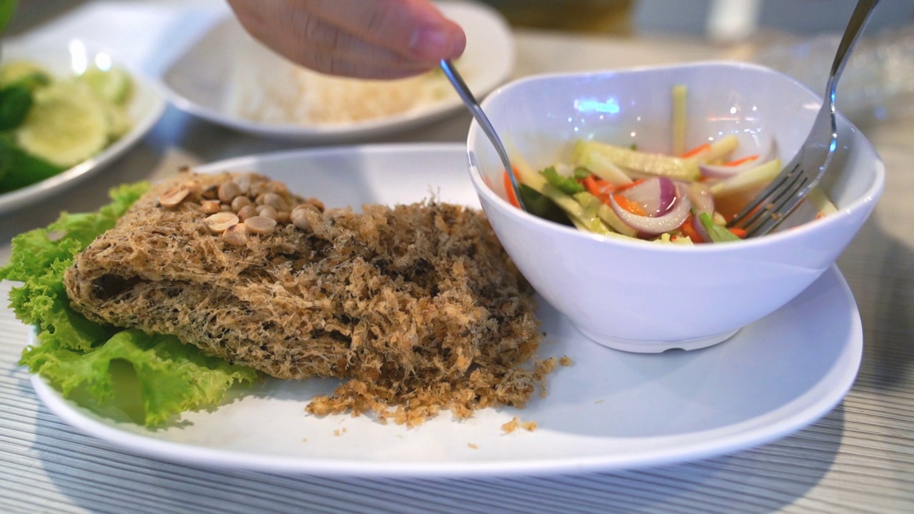 吃酥脆鲶鱼配芒果沙拉的人，泰国菜，慢动作视频素材