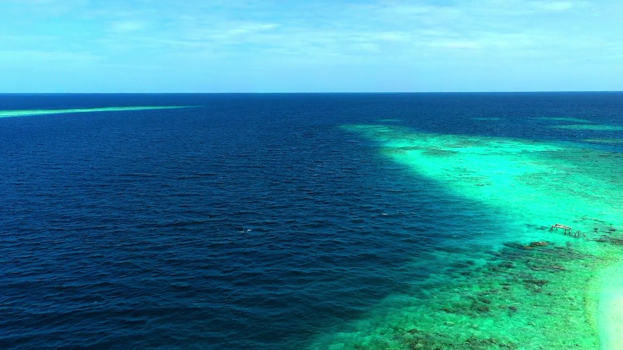 在晴朗的一天，岛上的航拍美景，无人机在云层下飞越蓝色波浪的海-马尔代夫的thulushoo视频素材