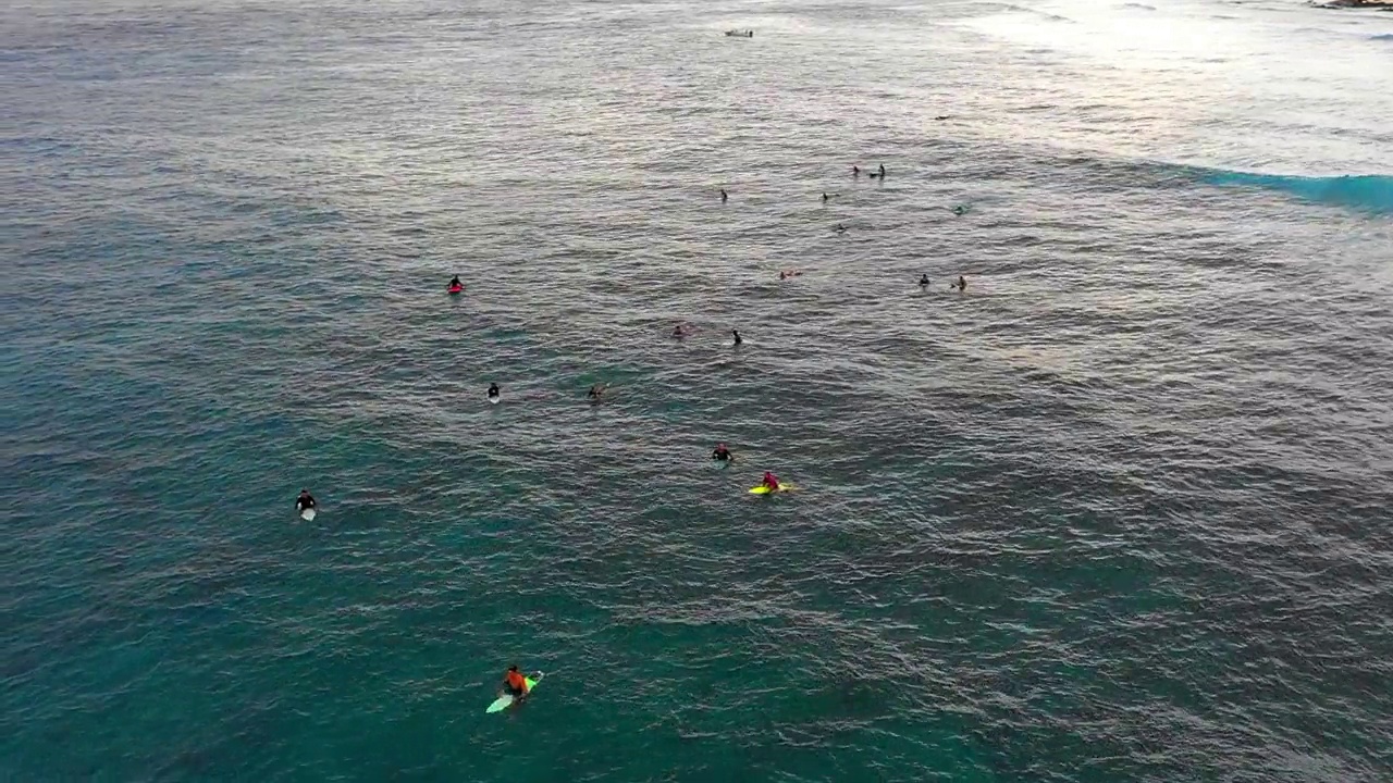 航拍:在小岛边用冲浪板游泳的人的平移镜头，无人机飞过波浪般的海面——马尔代夫的thulushoo视频素材